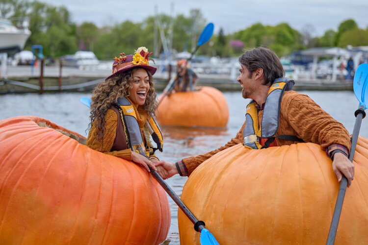 Hallmark Fall Into Love 2026: Full Schedule, Premiere Dates + Filming Locations Mishael Morgan and Corey Sevier boating through giant pumpkins and oars in a scene of Pumpkin Regetta Romance Hallmark's fall into love 2026